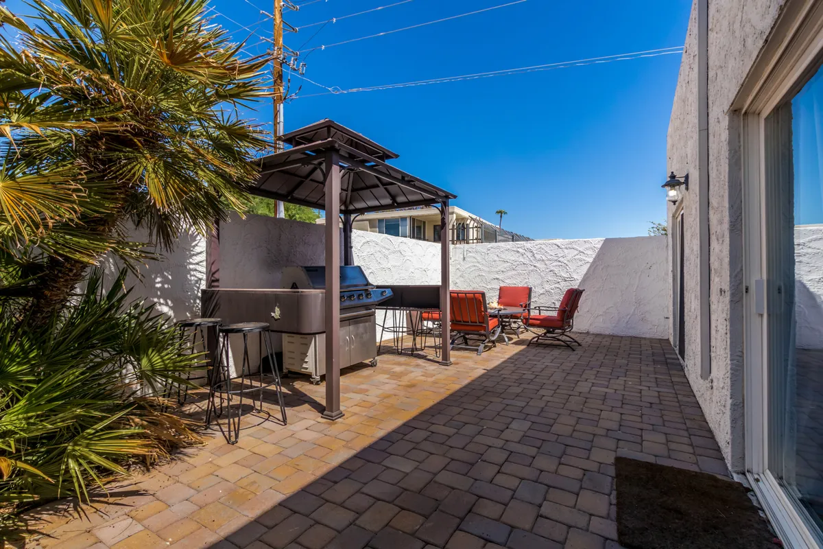 An inviting outdoor patio with a modern grill and red lounge chairs arranged on a paved area. The setup is ideal for socializing, barbecuing, or just enjoying Scottsdale’s pleasant weather. The scene feels casual and friendly, encouraging relaxation and mingling.