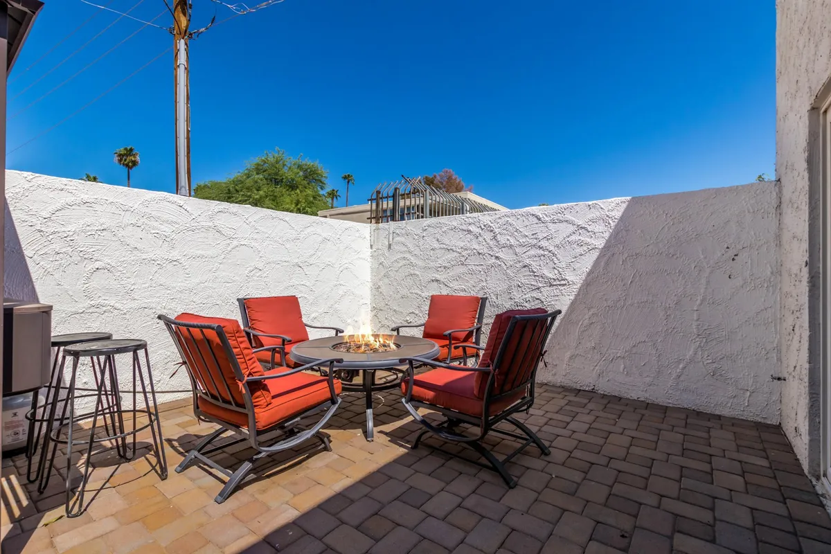 This image features a cozy exterior patio complete with a fire pit and red chairs set on a paved patio. The scene is intimate and inviting, suggesting a perfect spot for couples to relax together after exploring the city.