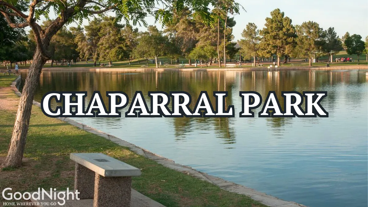 A tranquil lakeside park with calm water, park benches, and mature trees. The peaceful setting is ideal for walks, picnics, or simply pausing to enjoy the view. The natural landscape provides a refreshing break from urban activity and suggests nearby recreational options like Chaparral Park.