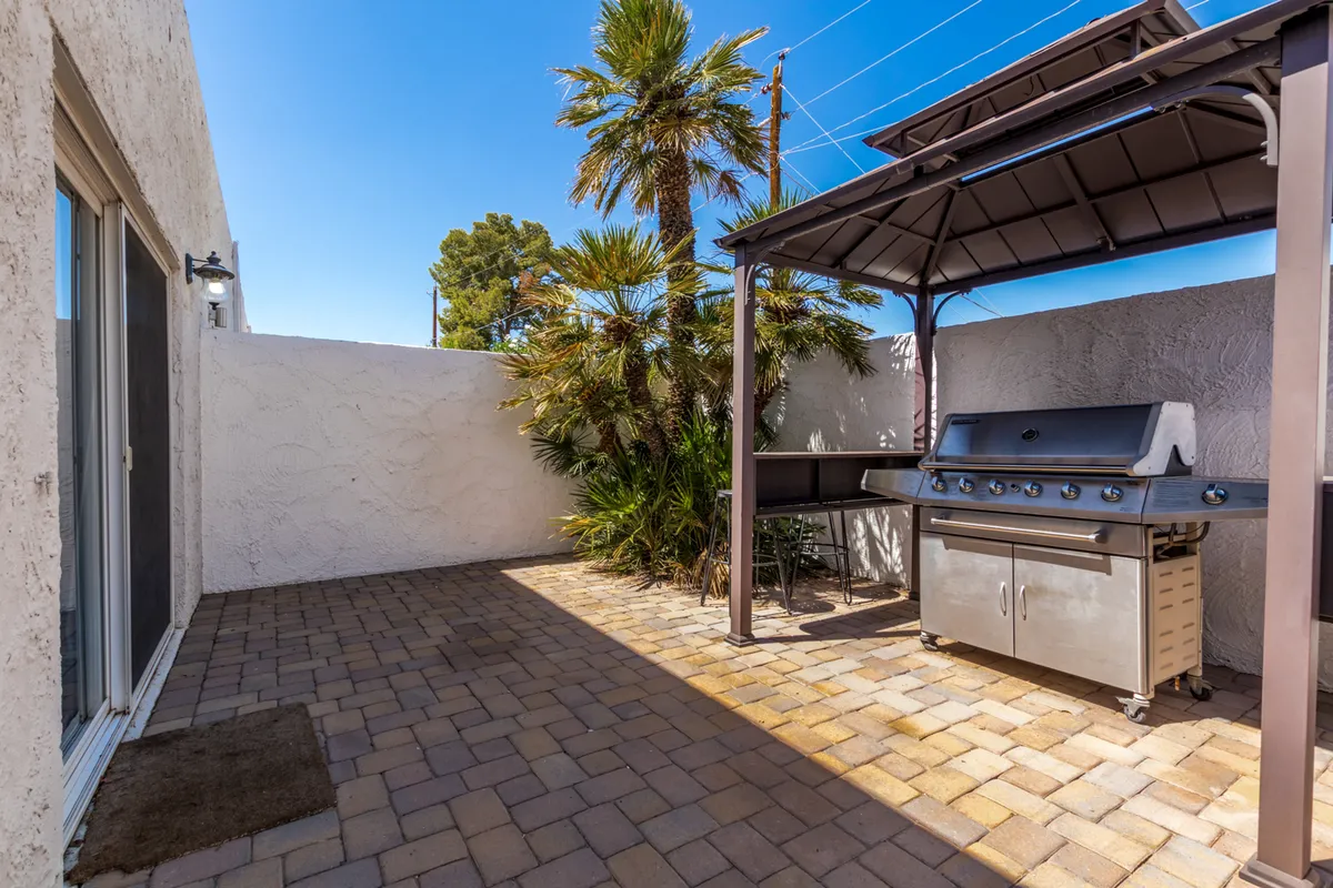 An inviting exterior patio area with a grill, comfortable outdoor seating, and swaying palm trees, perfect for gatherings and casual barbecues. The scene is set for both daytime relaxation and evening parties.